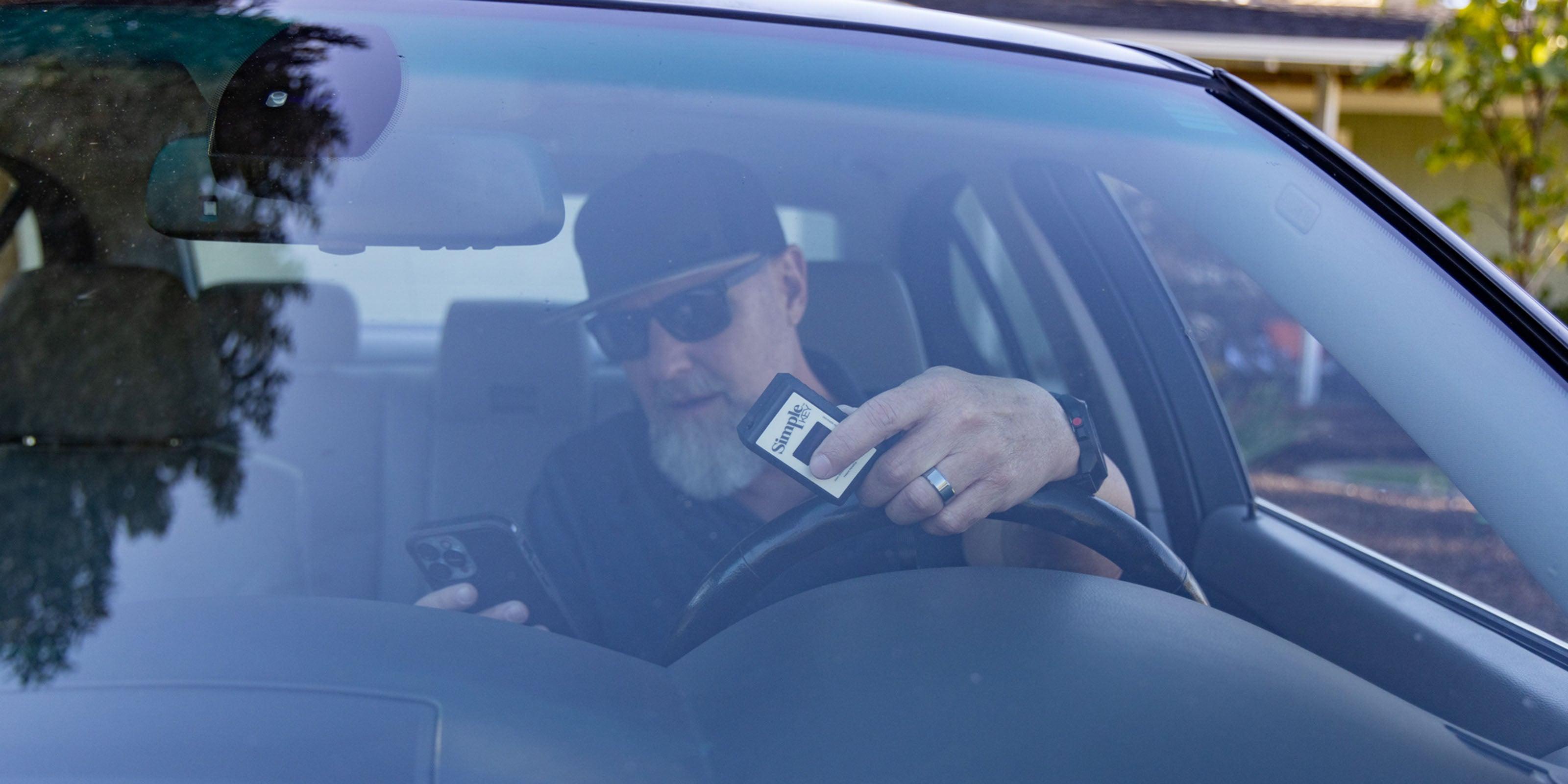 man holding key programmer and phone
